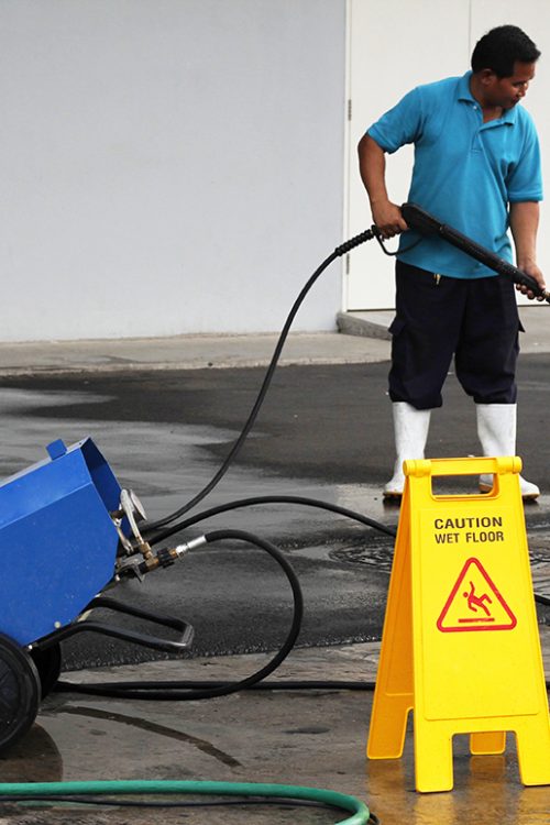 worker cleaning floor with air high pressure machine